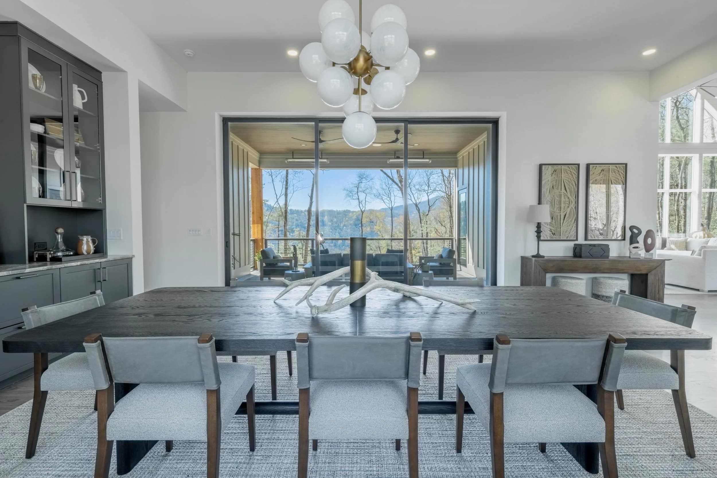 Dining room at Saratay Falls with a dark wood table, globe chandelier, and a view to the mountains.